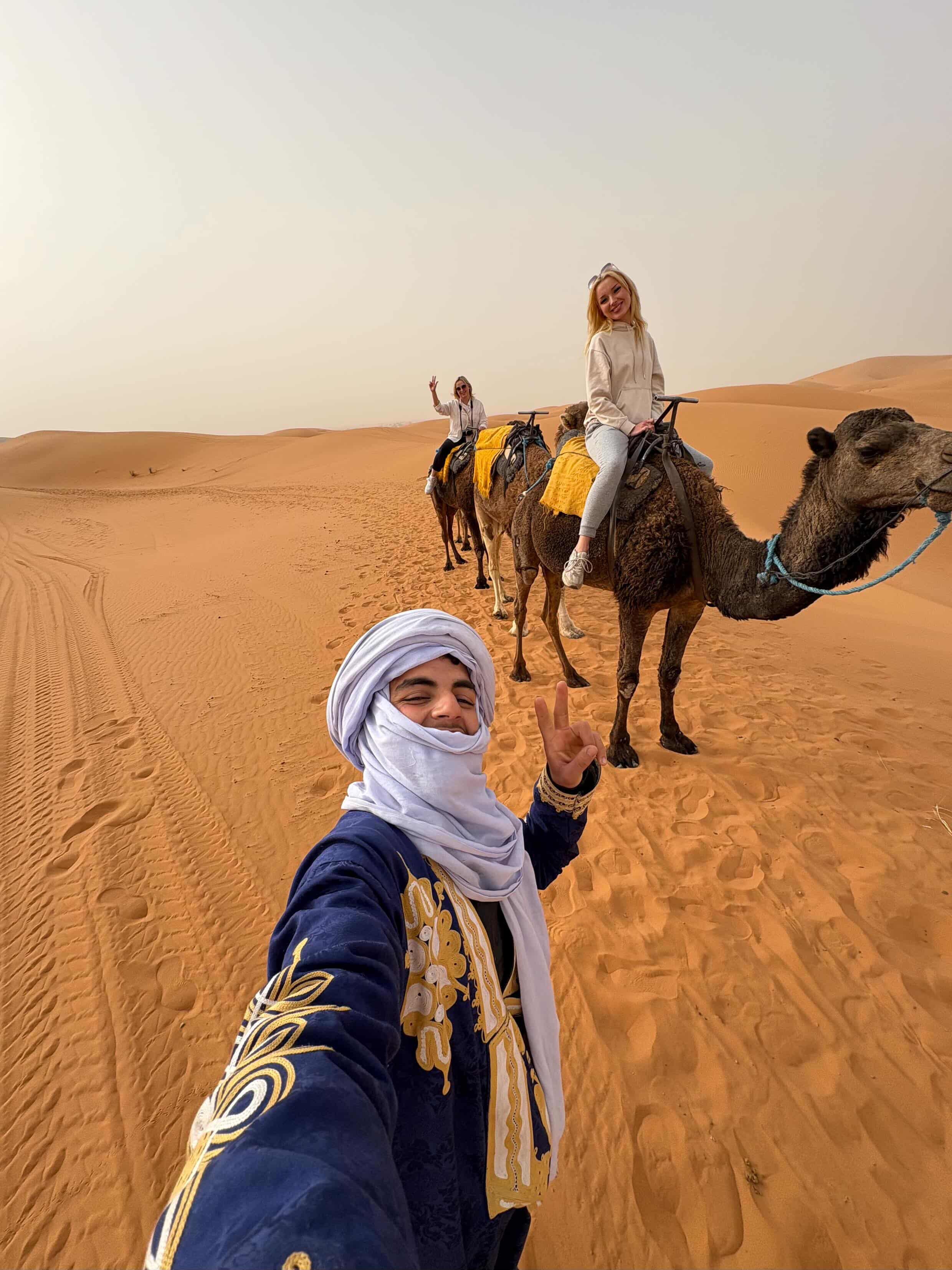 Private camel ride across warm Sahara dunes with local guide and guests in Morocco